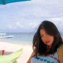 young beautiful and happy Asian Korean woman in chic Summer dress and sunglasses posing relaxed at tropical beach relaxed sitting on beanbag under umbrella parasol